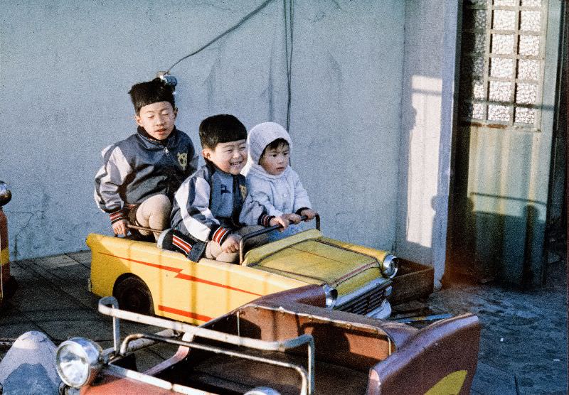Kids driving a toy metal car and wearing Yomiuri Giants jackets