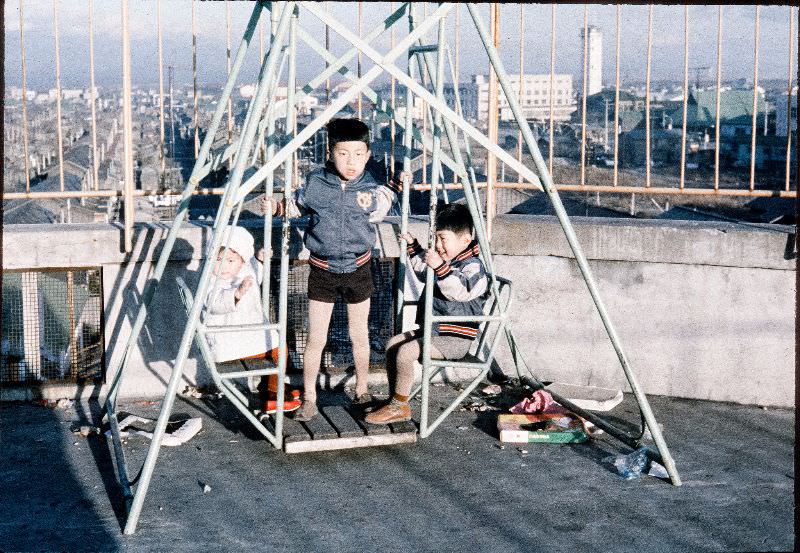 Kids wearing Yomiuri Giants jackets on a swing