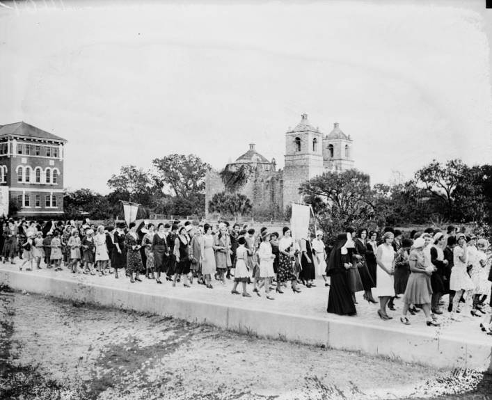 Feast of Christ the King procession from St. John's Seminary (background, left) to St. Peter's and St. John's Orphanage. Mission Concepción in background, 1930