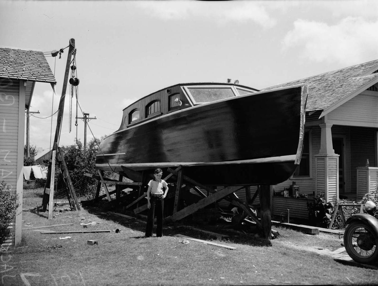 Portrait of Wallace Ingram standing in front of a 43-foot pleasure boat his father, Jack Wallace, 1936