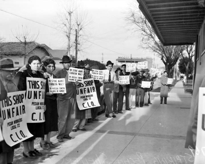 Striking pecan shellers picketing on the sidewalk in front of the Southern Pecan Shelling Company at 135 East Cevallos Street, 1938