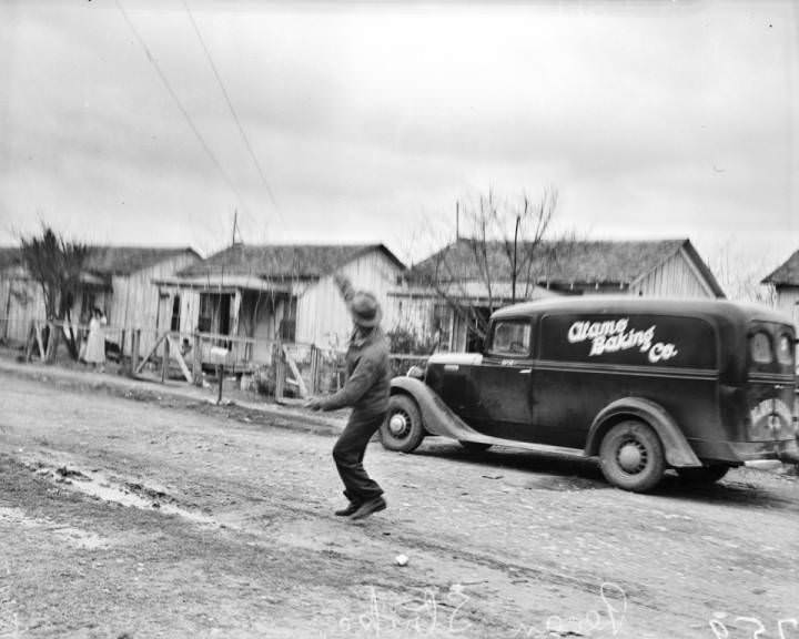 A striking pecan sheller throws a stone as he stands in the street, 1938