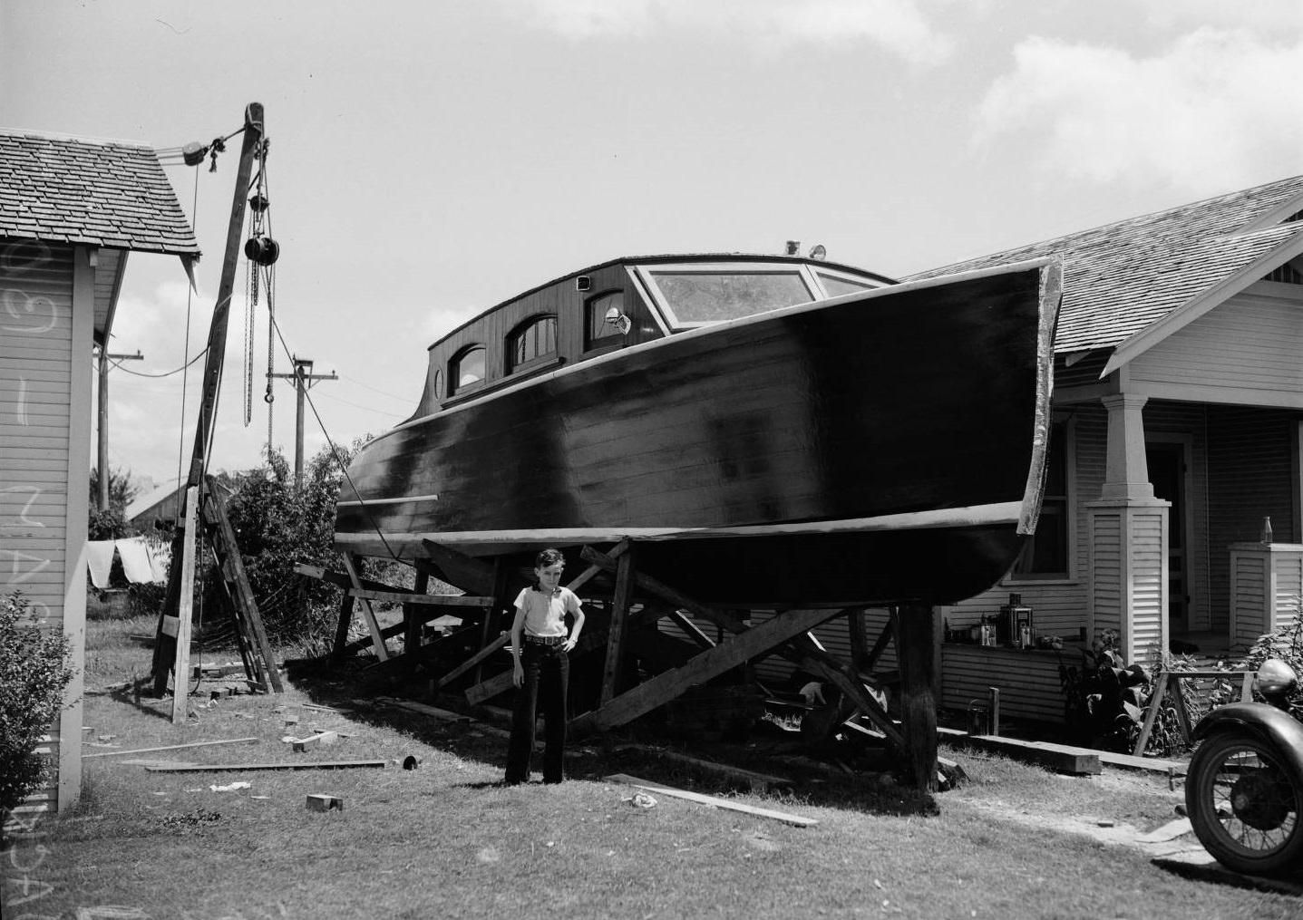 Portrait of Wallace Ingram standing in front of a 43-foot pleasure boat his father, Jack Wallace, had recently completed building, 1936