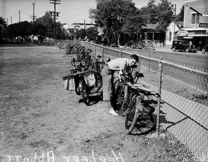 Herbert Abbott chaining bicycle to fence, 1937
