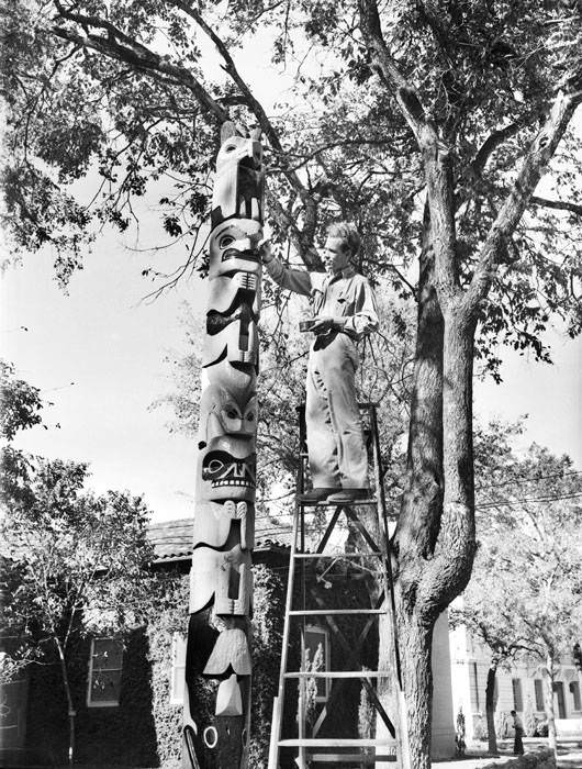 Jack Davenport, archaeologist, repainting a Tongan totem pole donated by Porter Loring which stands in front of the Witte Museum, 1938