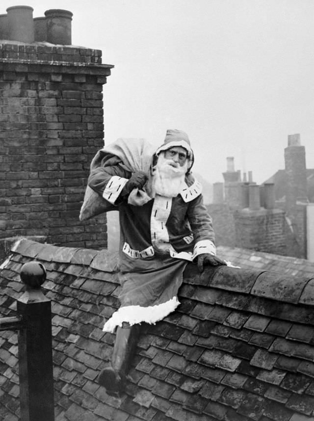 A sponsored Santa Claus searching for a chimney on the rooftop, Rye, Sussex, 1950.