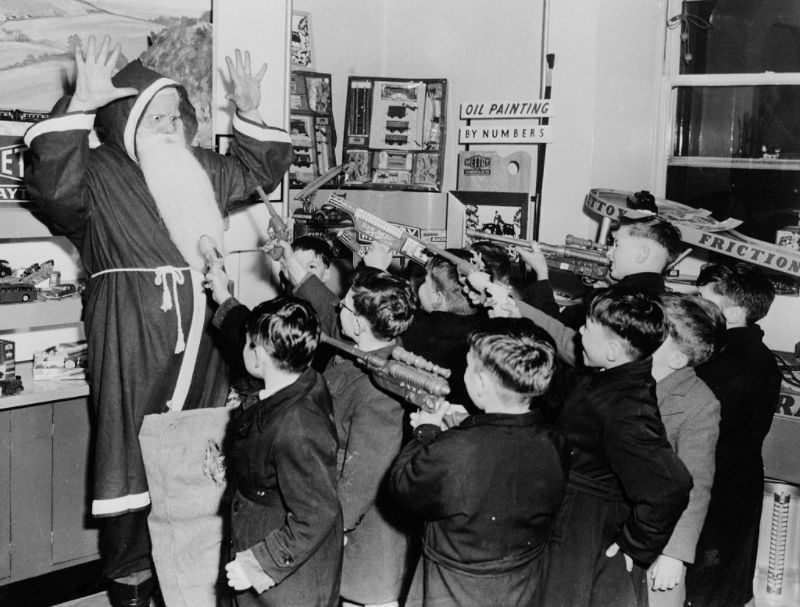Santa Claus held up by a group of boys armed with toy guns, London, 1954.