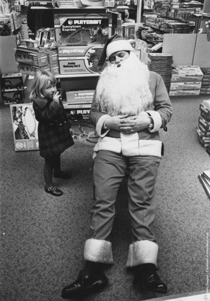 A young girl finds Father Christmas asleep at Bourne And Hollingsworth store in Oxford street, London, 21st December 1976