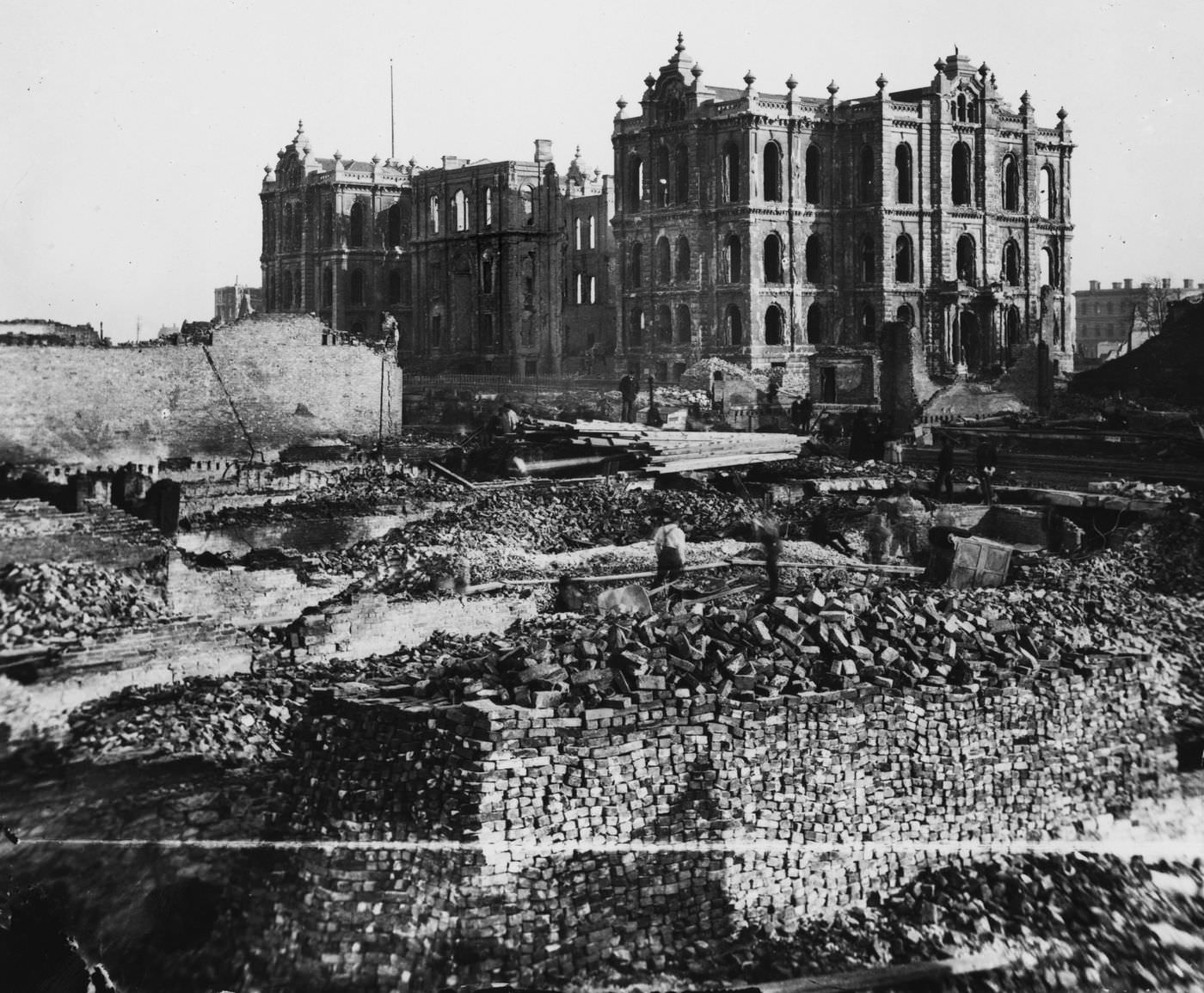 Workers walk through the wreckage near the remains of the courthouse and City Hall, background, in the aftermath of the Great Chicago Fire.