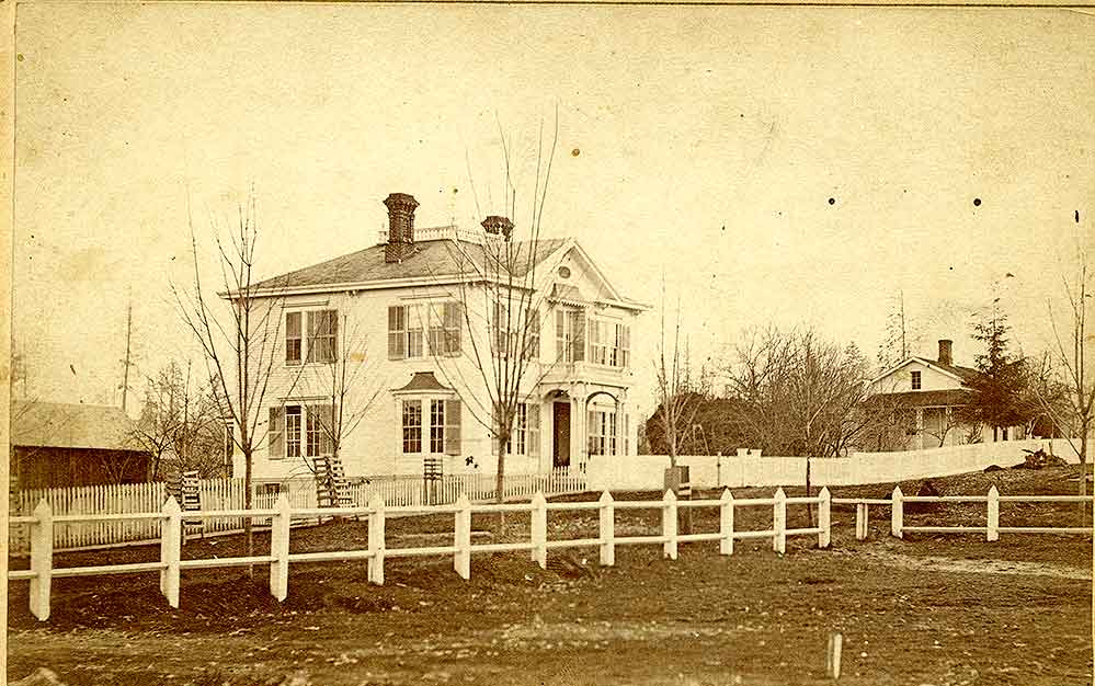 Two story white clapboard home, identified as the McElroy Home on 702 Washington Street, Olympia, 1874.