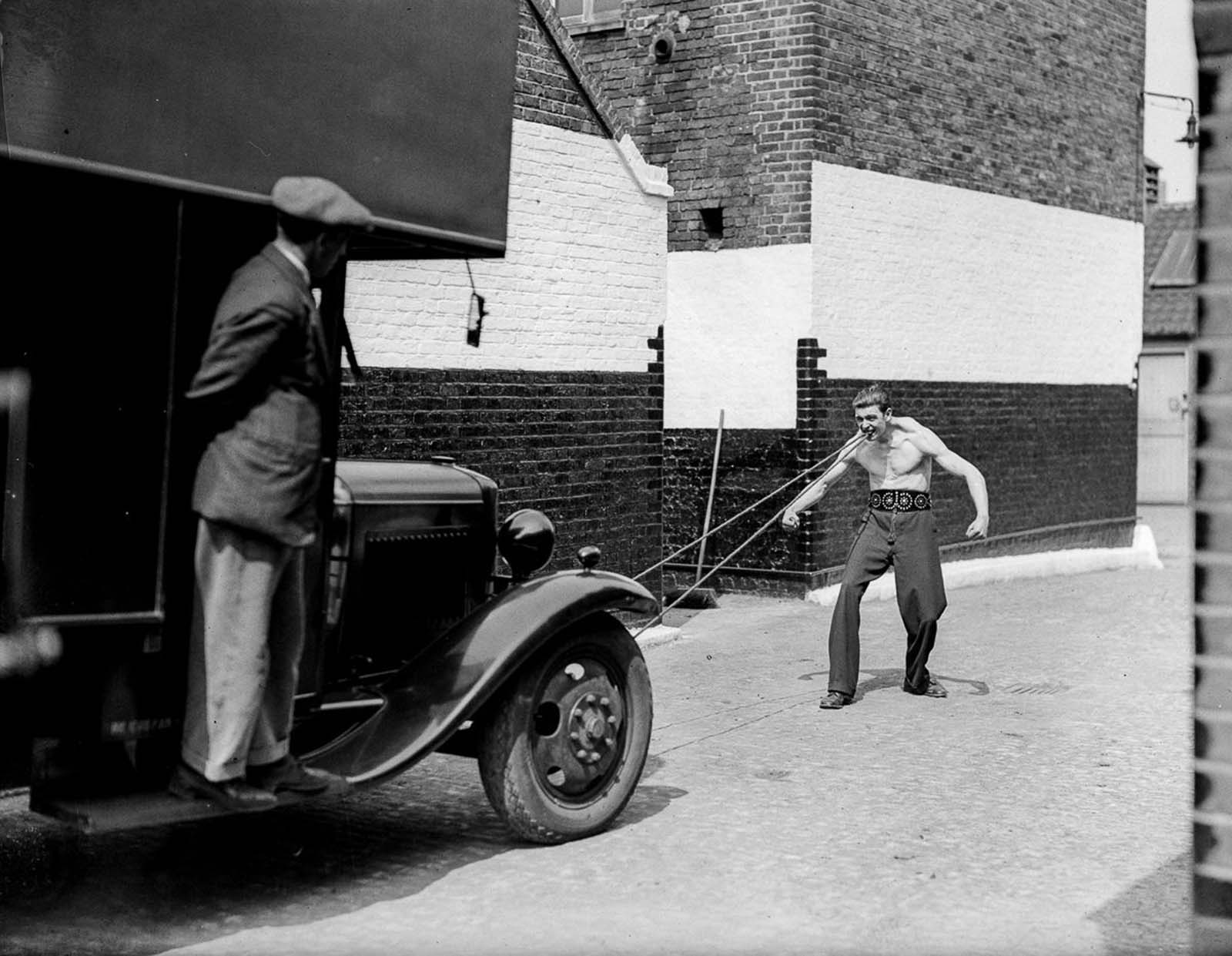 J. Rolleano pulls a truck with his teeth, 1932.