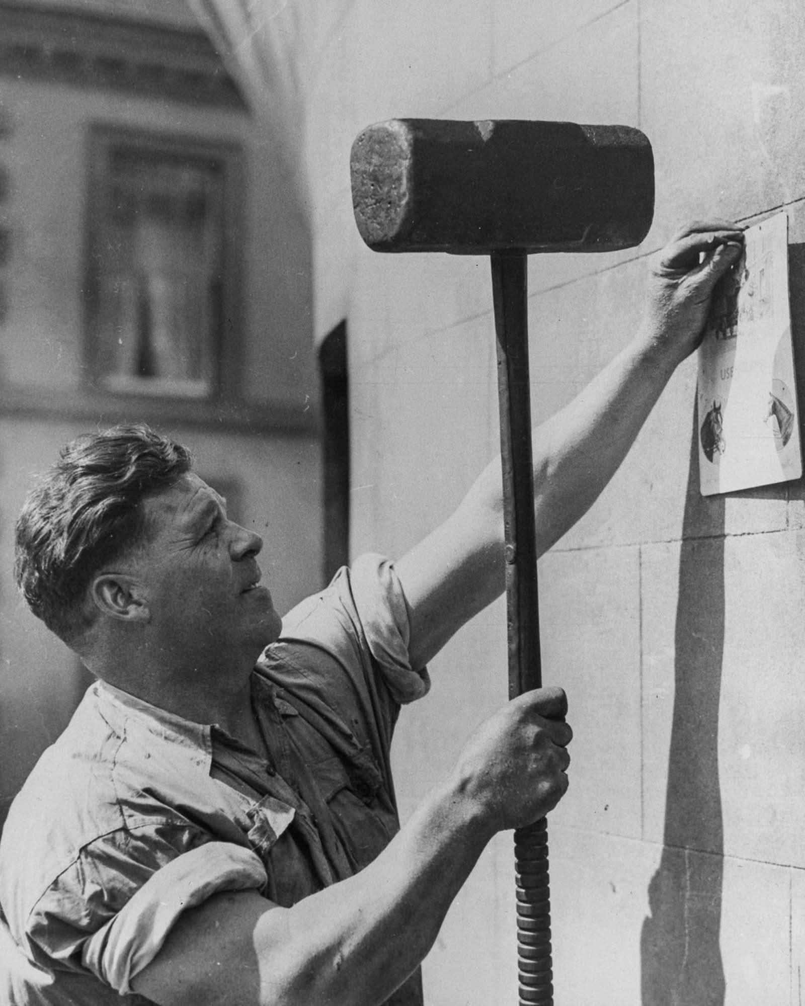 Joe Price uses a 50-pound hammer to nail up a notice, 1934.