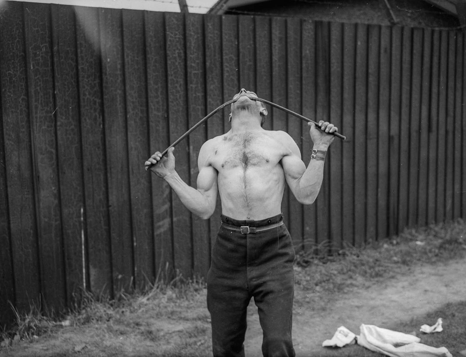 George Challard bends an iron bar with his teeth, 1935.