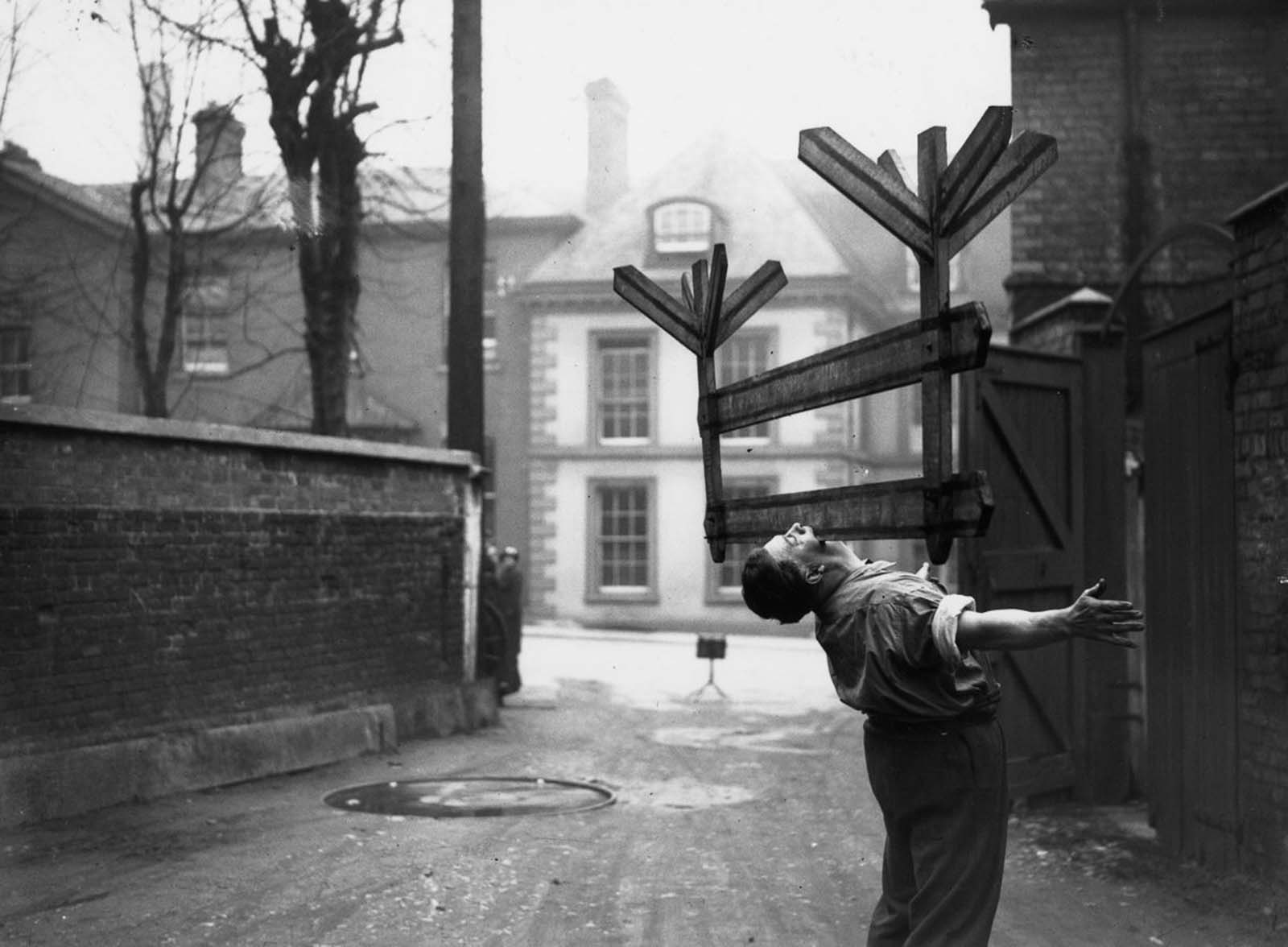 Joe Smith, a blacksmith from Gloucester, picks up and balances a roadworks notice in his teeth, 1936.