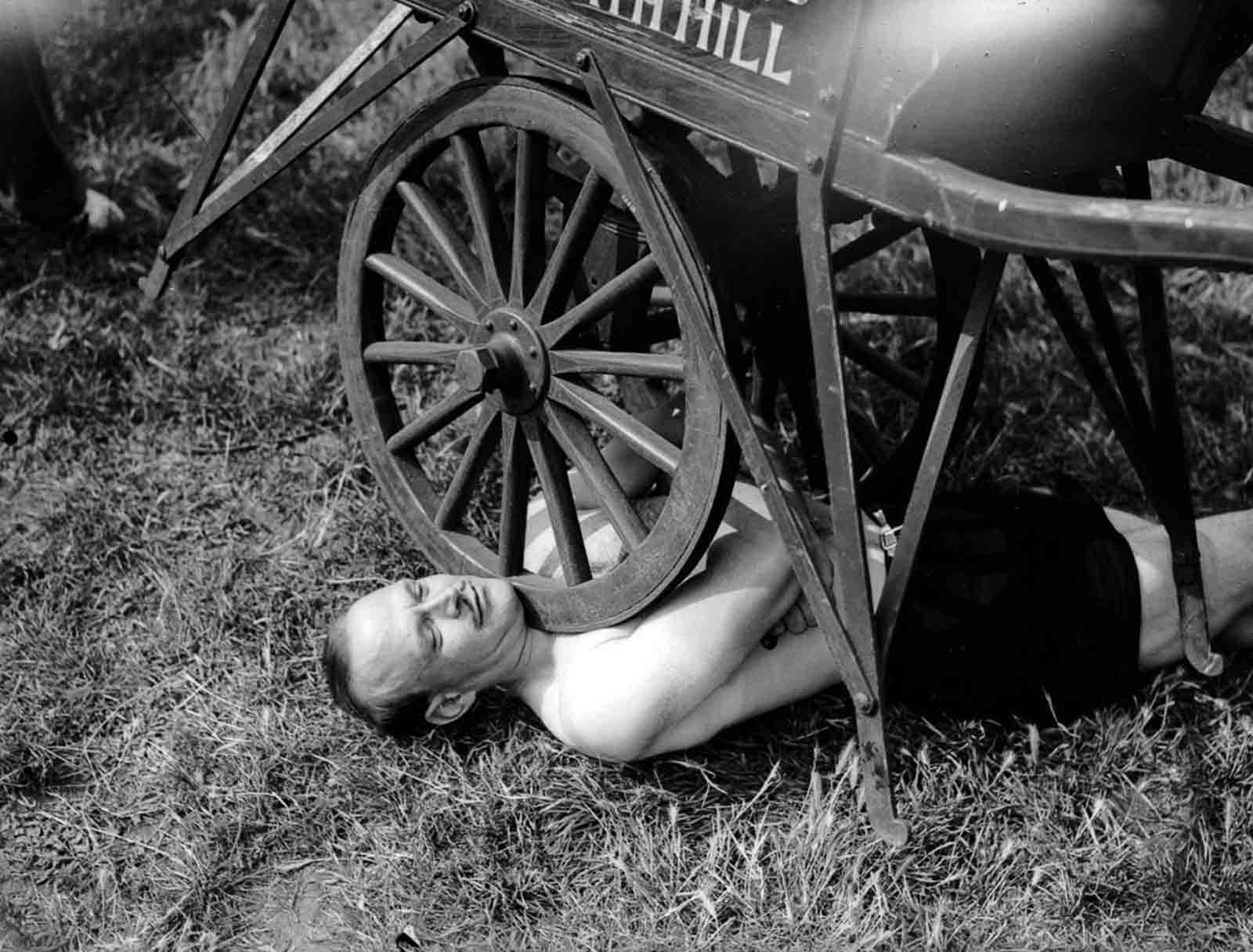 Jean Challard, who claimed to be the world’s champion steel bender and strong-man, supports the weight of a push-cart on his windpipe, 1938