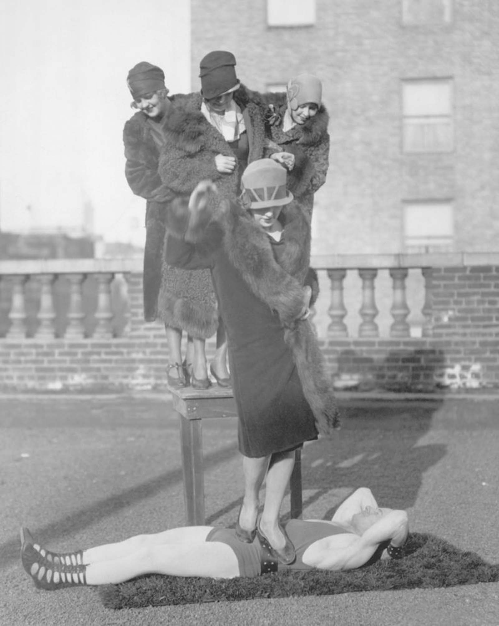 Andre Reverdy demonstrates his core strength by having women jump on his mid-section from a table, 1920s