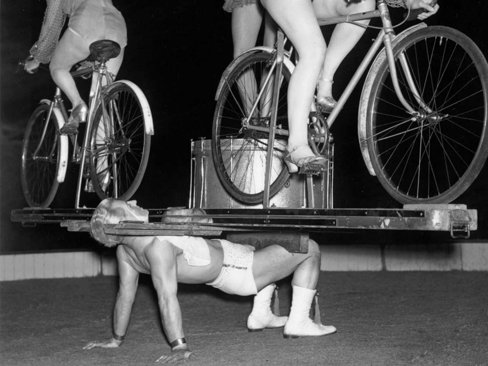 Strongman Mr. Briton balances tow cyclists and a dancer on his chest in Harry Benet’s circus at Chiswick Empire in London, England on Sept. 4, 1945