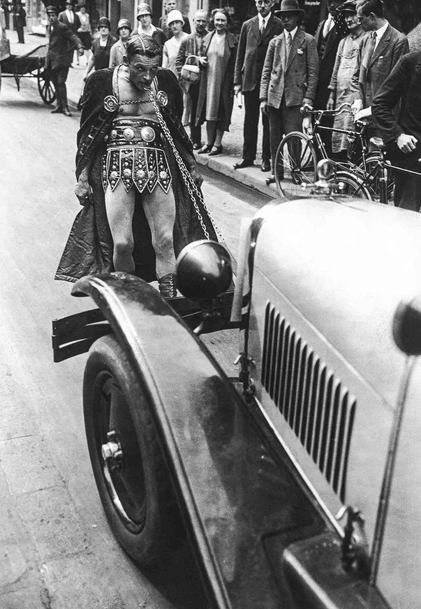 Circus strongman Stefan demonstrates his strength by towing a motorcar with his teeth through the streets of Berlin, 1925.