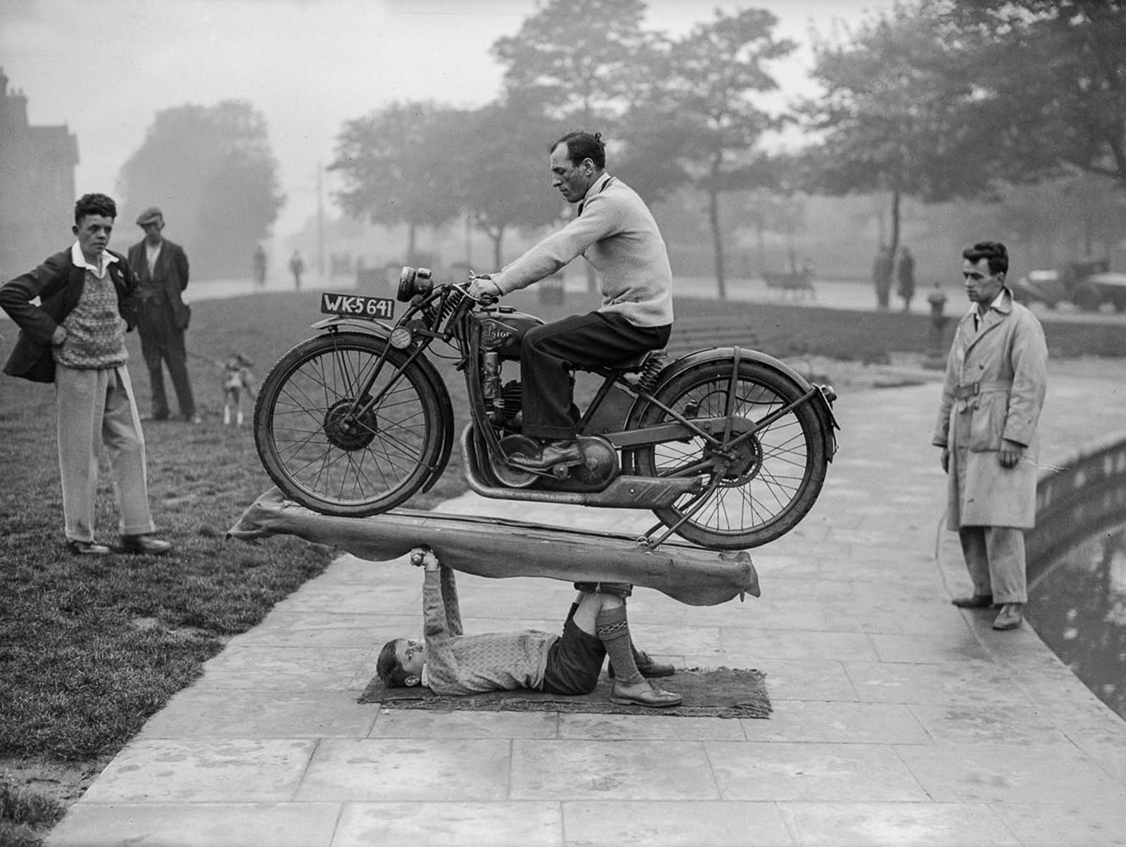 A 14-year-old calling himself “Boy Samson” supports a 200-pound motorcycle and its rider, 1932.