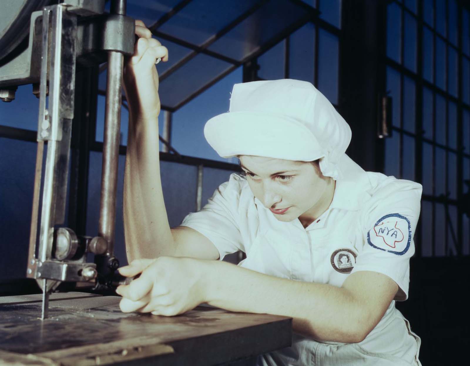 Mildred Webb, an NYA trainee at the base, learns to operate a cutting machine in the Assembly and Repair Department.