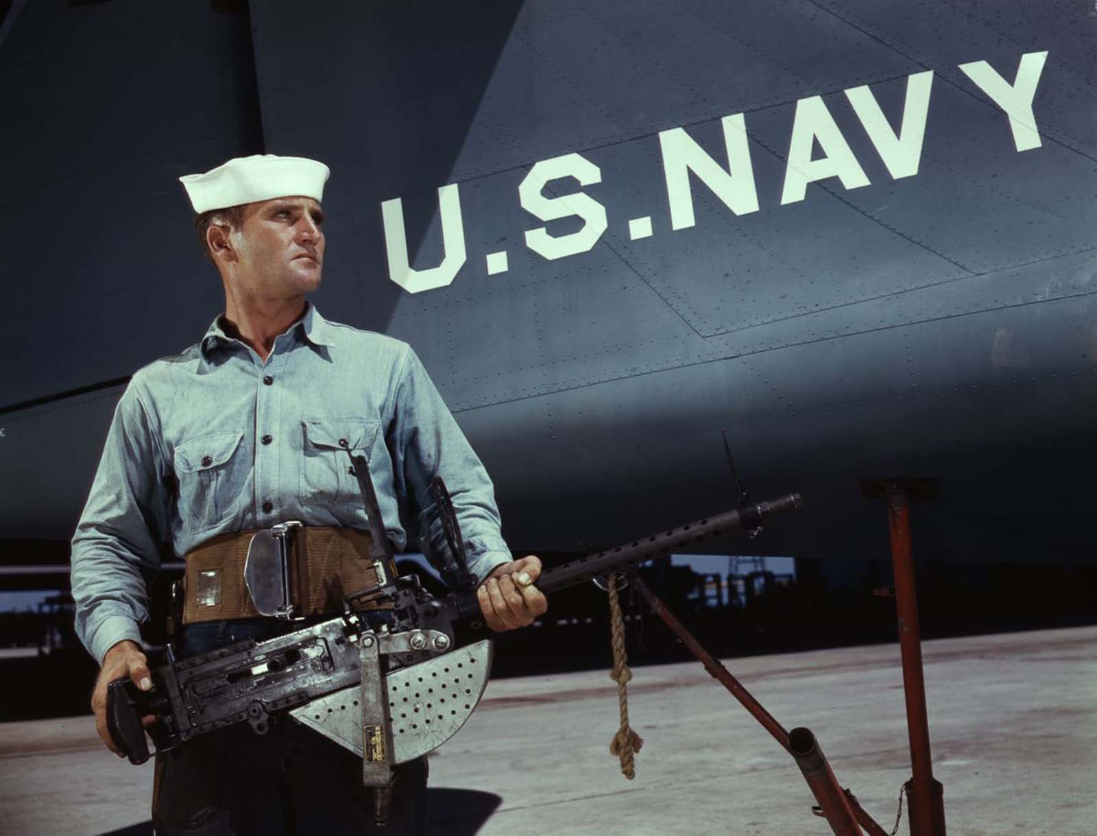 J.D. Estes, a seven-year veteran of the Navy, hefts a machine gun to be installed in a plane.