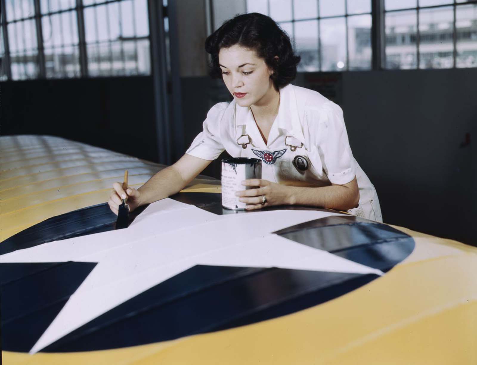 Irma Lee McElroy, a former office worker, paints an insignia on an airplane wing.