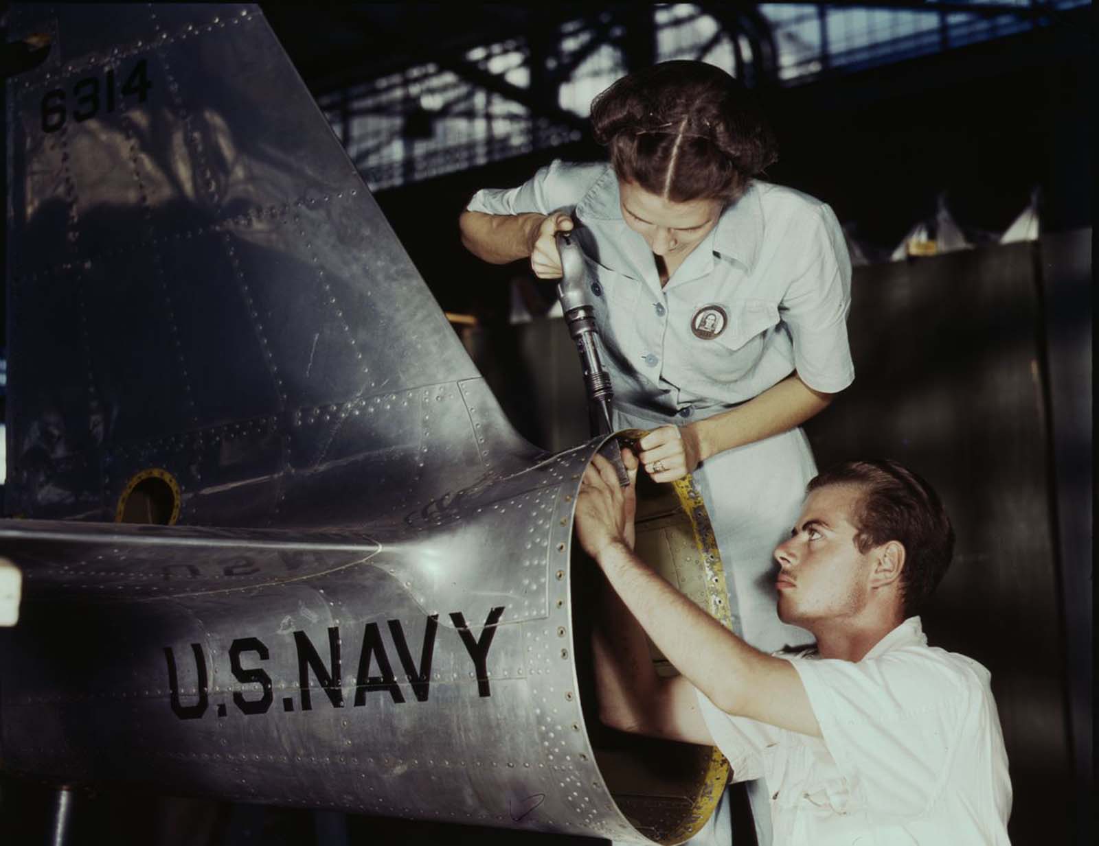 Virginia Davis, a riveter in the assembly and repair department of the Naval Air Base, supervises Charles Potter, an NYA trainee from Michigan.