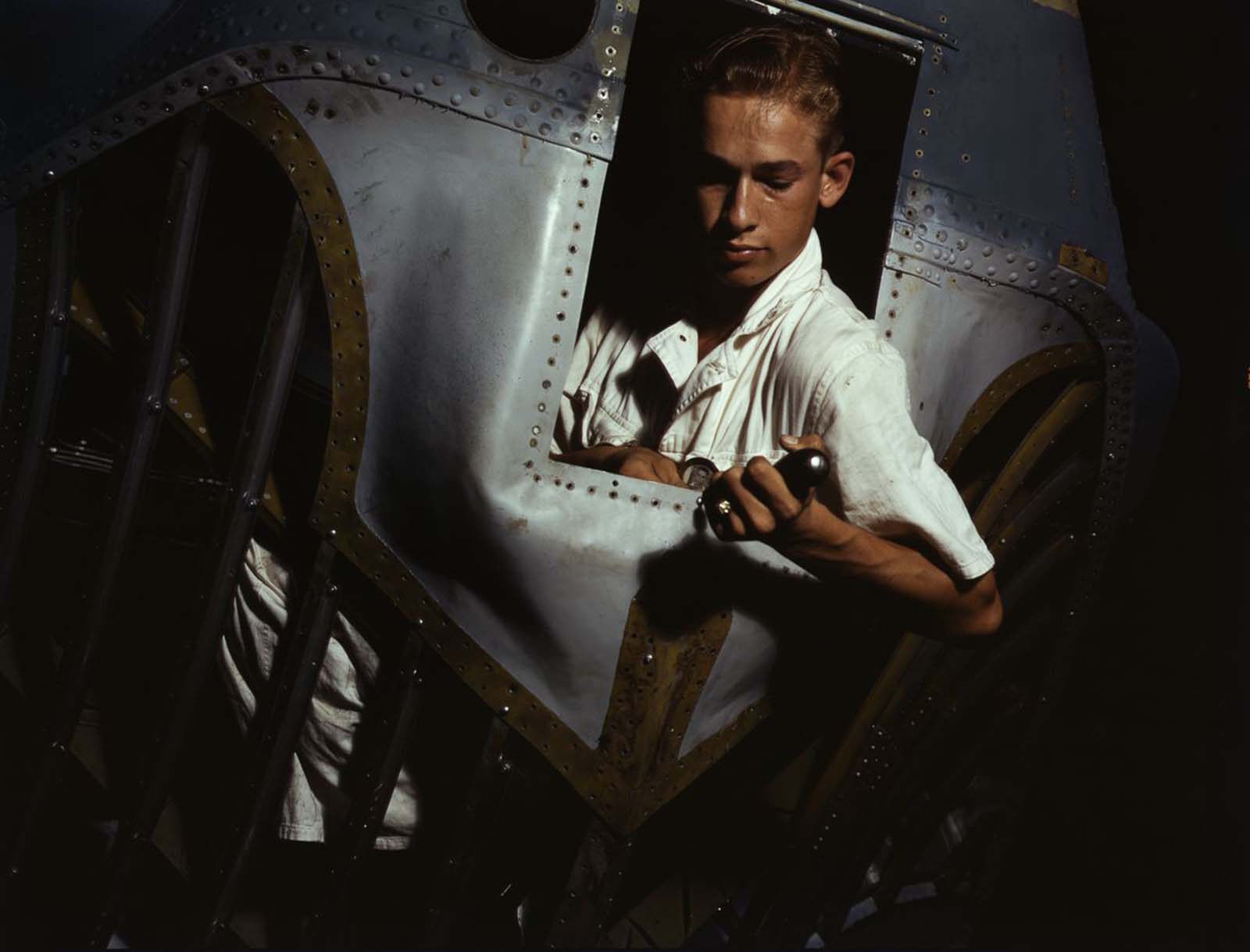 Working inside the nose of a PBY, Elmer J. Pace learns the construction of Navy planes.