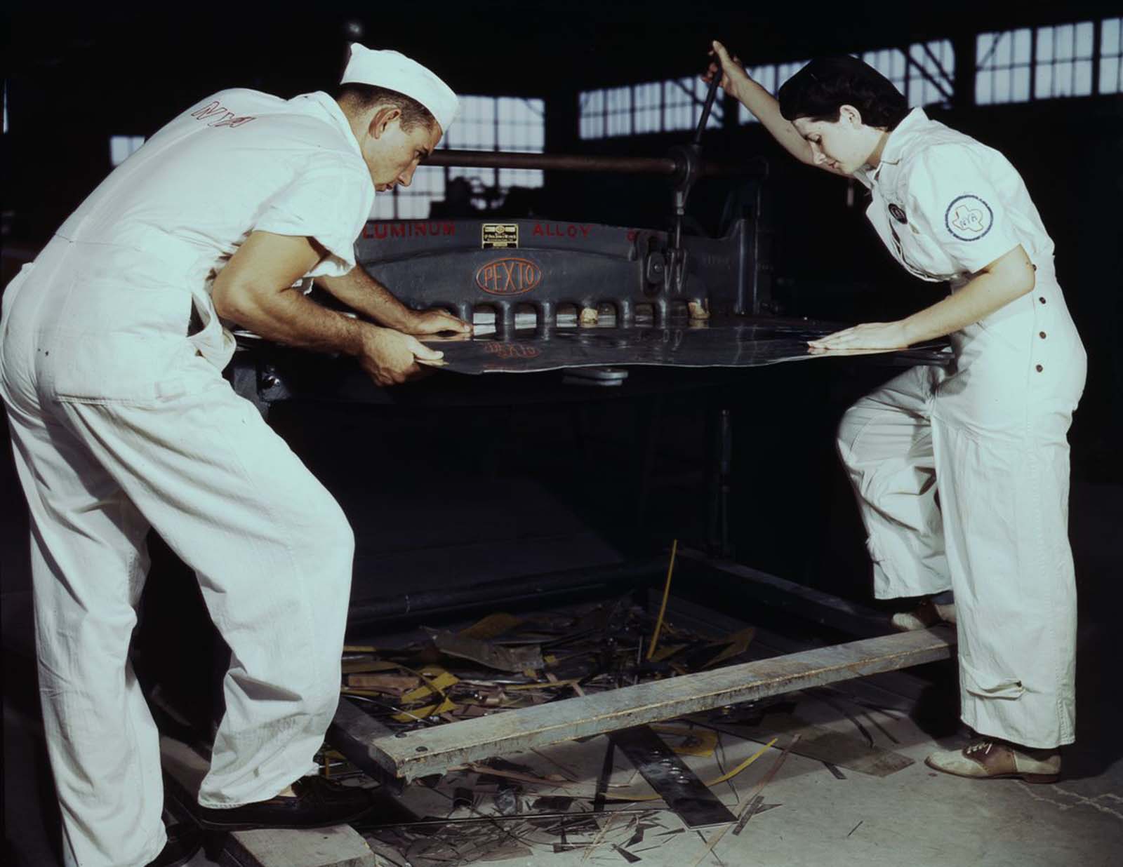 Learning to work a cutting machine, two NYA employees receive training to fit them for important work.