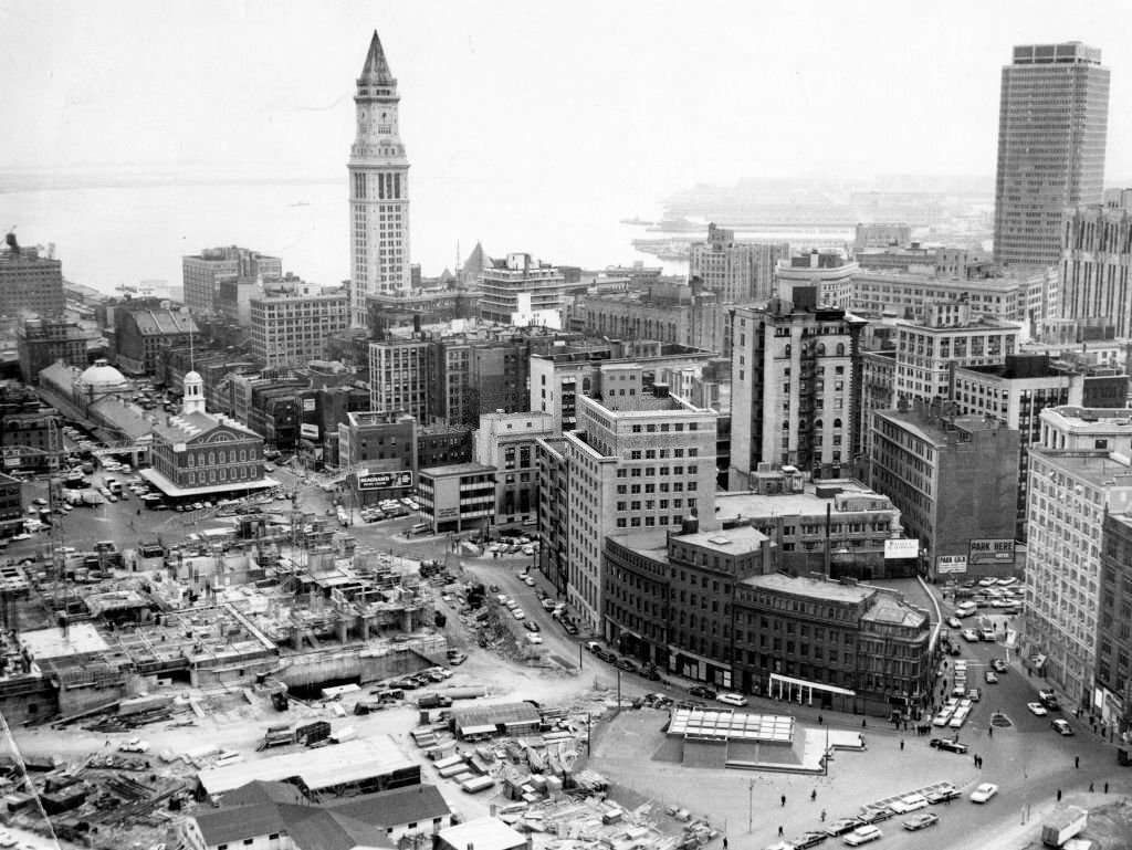 An aerial view of downtown Boston, looking over construction site of the new City Hall, Faneuil Hall, and the Custom House to Boston Harbor, 1965.