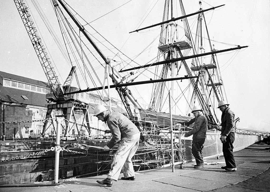 Workers erect fence around the Charlestown Navy Yard in Boston to protect visitors while the USS Constitution is in dry dock undergoing repairs on December 10, 1963.