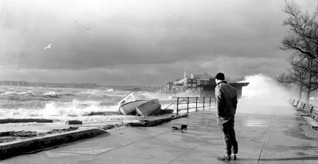 An observer watches waves crashing on the beach near Kelly's Landing restaurant in the City Point neighborhood of South Boston, 1963.