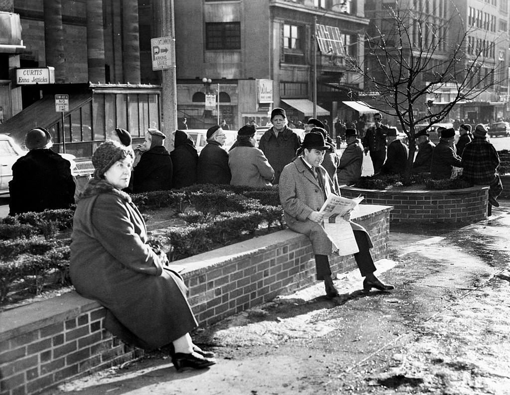 People sit on the planters on the Tremont Street Mall near Park Street in Boston, enjoying a warm spring sun in the middle of winter, Jan. 10, 1963.