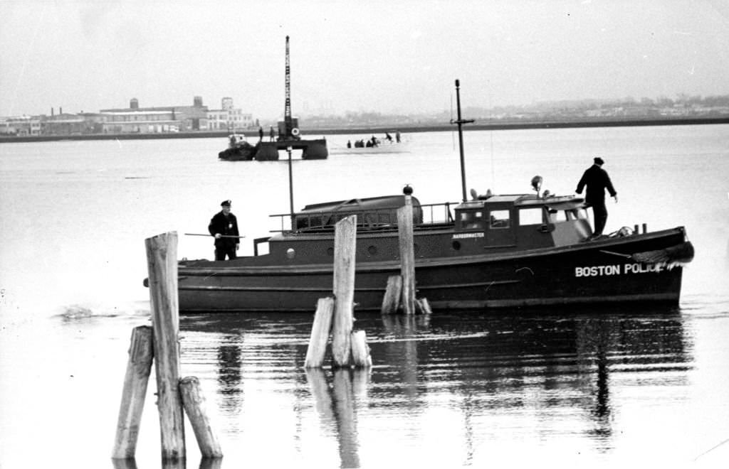 Boston Police officers search for a boat which sank after a fire near the Savin Hill Yacht Club in Boston's Dorchester, 1962.