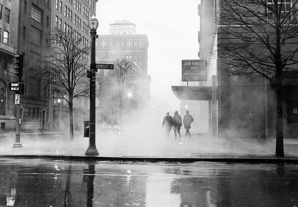 Ground fog swells up around three pedestrians walking past the entrance to John Hancock Hall and the Dorothy Quincy Suite at Stuart and Berkeley Streets in Boston at 6:30 a.m. on March 5, 1967.