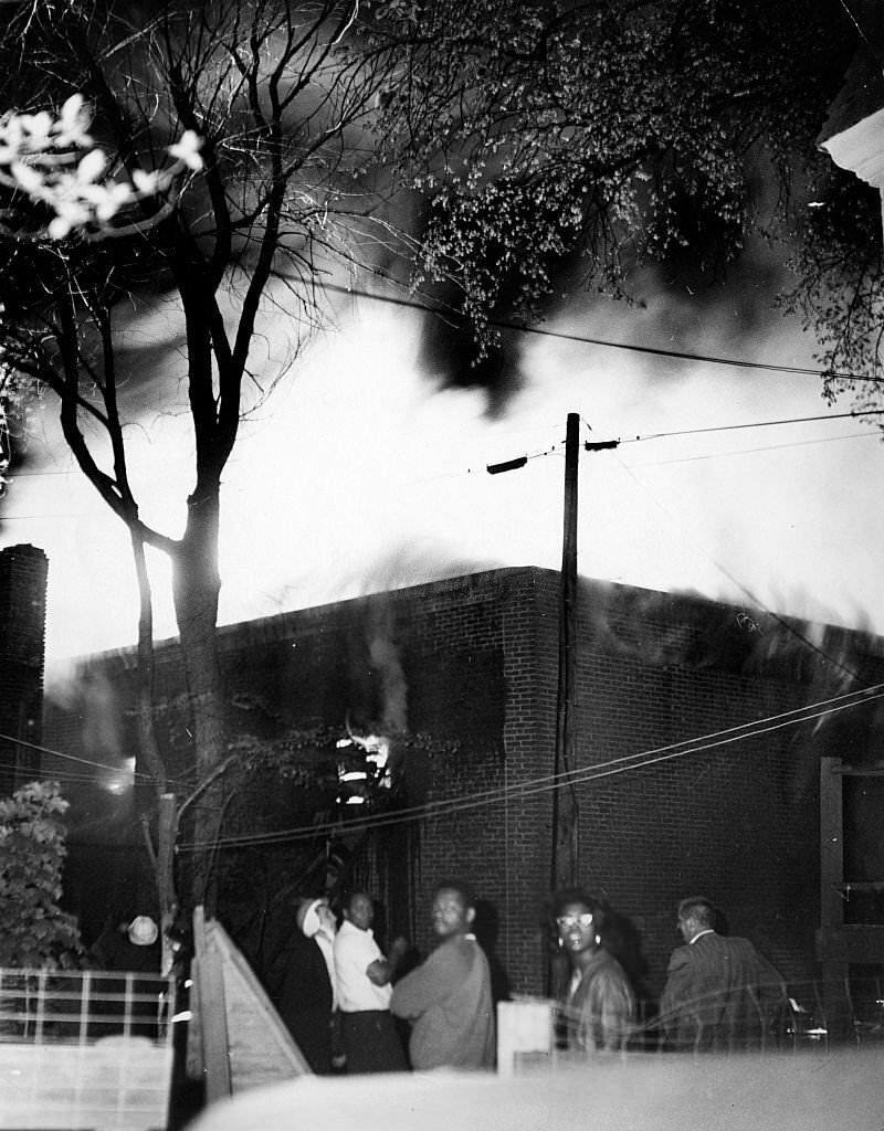 People watch as a three-alarm fire burns in a paint store on Blue Hill Avenue in the Roxbury neighborhood in Boston on June 3, 1967.