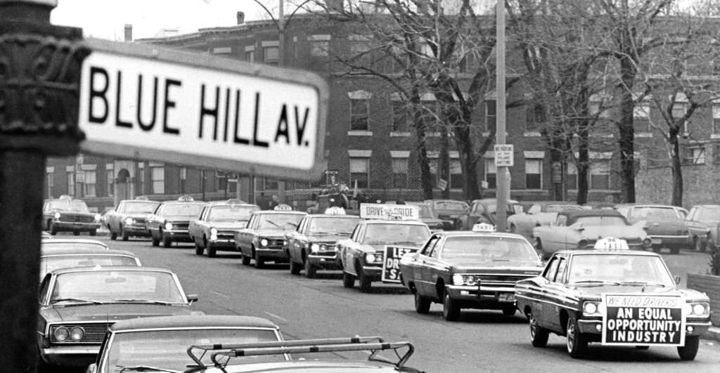 A motorcade of taxi cabs proceeds through the Grove Hall section of Dorchester in Boston as about 200 Boston taxi drivers stages a tribute to a slain fellow driver on March 20, 1969.