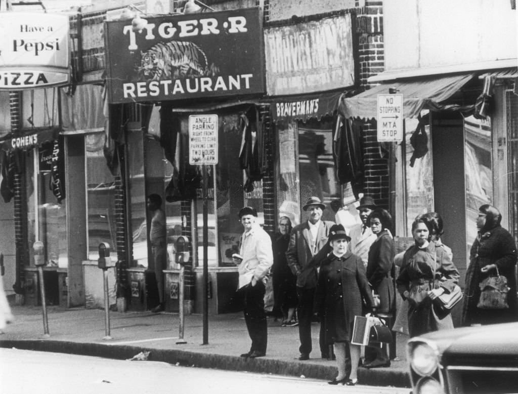 People wait for the bus at an MTA stop next to the Tiger Restaurant on Blue Hill Avenue in Boston on May 4, 1969.