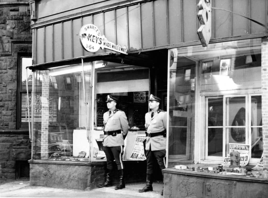 Massachusetts State Troopers John Riordan and Kenneth Maurais stand outside of the Swartz Lock Shop at 364 Massachusetts Ave. in Boston following a gambling raid on Oct. 26, 1961.