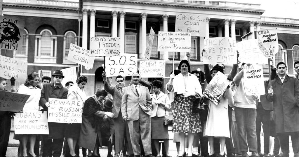 Demonstrators hold signs during a protest against Cuban Prime Minister Fidel Castro in front of the Massachusetts State House in Boston on April 23, 1961.