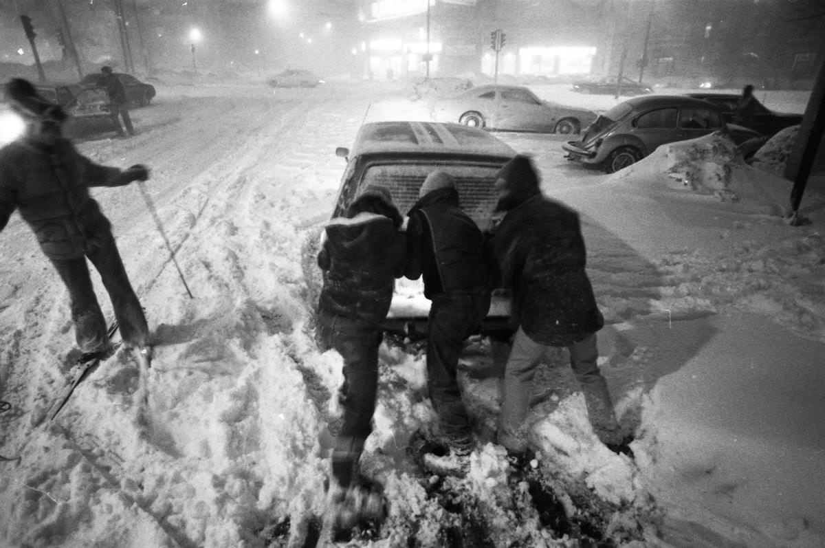 Three people pushed a disabled car as a skier passed on Kelton Street near Commonwealth Avenue in Boston.