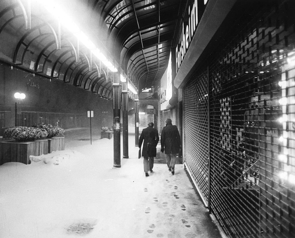 People walk by closed shops at night Washington Street near Bromfield in downtown Boston following the historic "Blizzard of 78".
