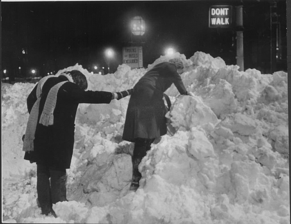 Pedestrians climb through tall piles of snow left behind by the "Blizzard of 78", while crossing the street near Commonwealth Avenue in Back Bay on Feb. 10, 1978.