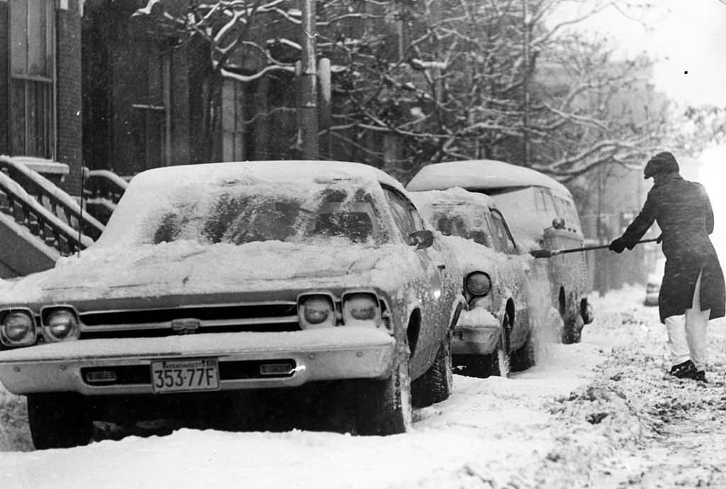Resident Willie Samuel brushes snow off a car on Massachusetts Avenue in Boston, 1971.