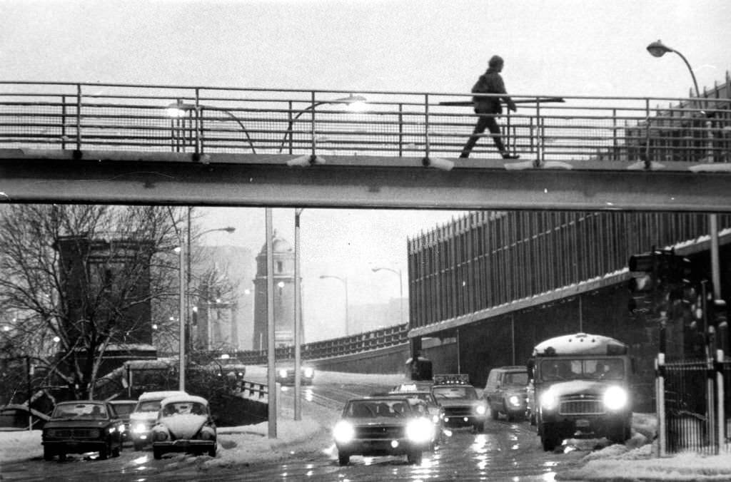 Charles Street Circle in Boston glistens as vehicles pass through rain and slush coming off the Longfellow Bridge in the early morning, 1970.