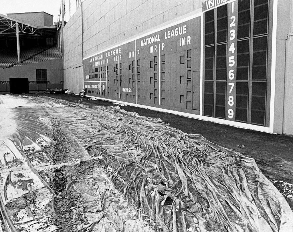 Snow removal has begun at Fenway Park, with the field now showing through the sea of plastic covering it, seen near the scoreboard on March 12, 1969.