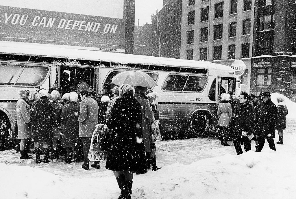 A crowd boards a bus in the snow on Summer Street in Boston in 1969 after the third major snow storm of the year.