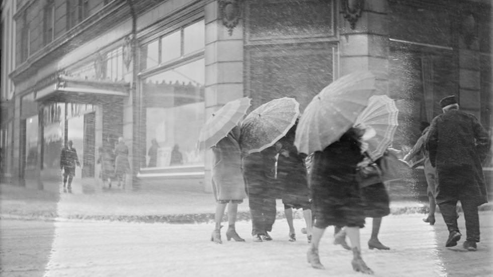 Women use umbrellas to ward off snow, during snowstorm in downtown Boston, 1930