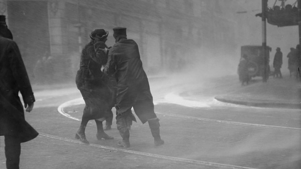 Police officer helps woman through blinding snow during a blizzard in Boston, 1920