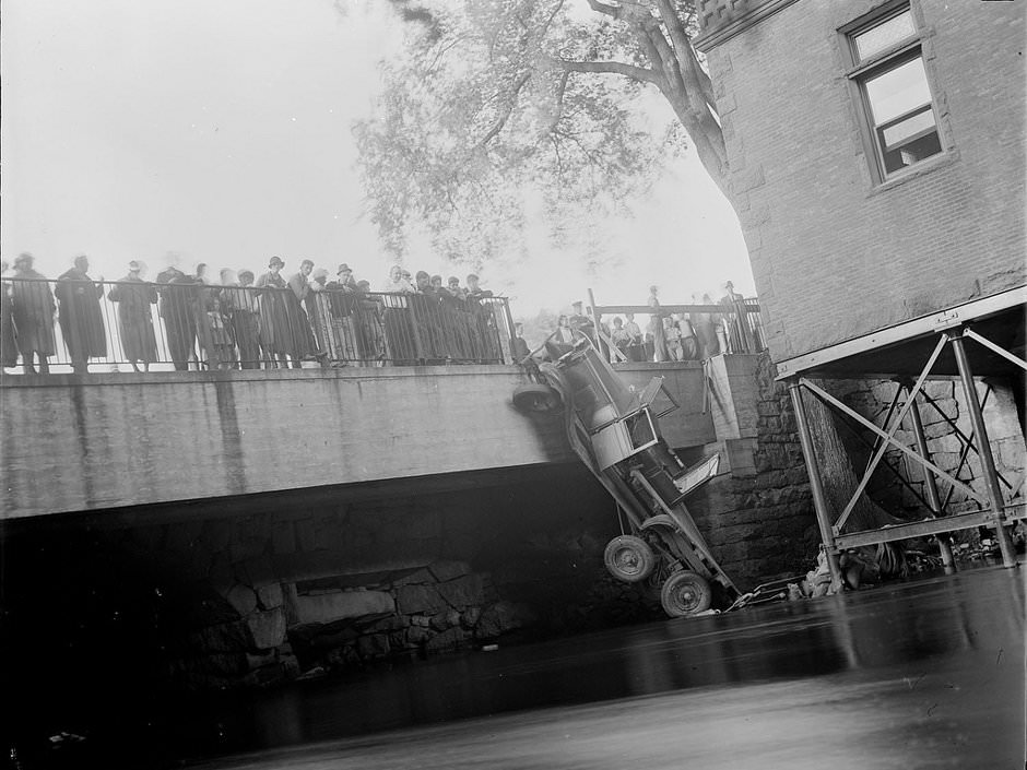Truck hangs by wheel off bridge, 1934